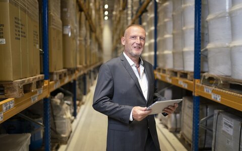 EWE business Referenz In-Time Mann mit Tablet in Lagerhalle