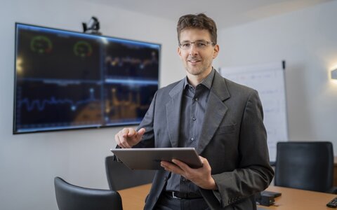 EWE business Referenz iaS Mann mit Brille und Jacket und Tablet in der Hand