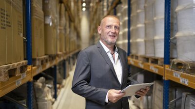 EWE business Referenz In-Time Mann mit Tablet in Lagerhalle