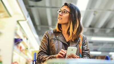 Kommunikationslösungen für den Handel Eine Frau, die in einem Markt Waren aussucht
