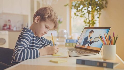 Hausaufgaben mit Online-Unterstützung Ein Junge macht Hausaufgaben vor einem Rechner, auf dem Online-Unterricht läuft.