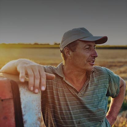 Fahrplanoptimierung in der Direktvermarktung mit EWE business Ein Landwirt lehnt an einem Trecker auf einem Feld.