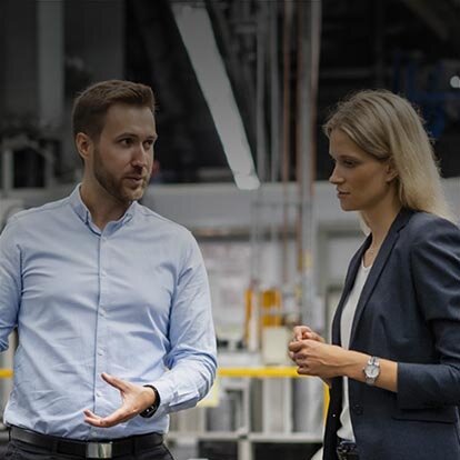 Nutzen Sie Regelenergie in der Direktvermarktung mit EWE business Eine Frau und ein Mann besprechen etwas in einer Produktionshalle.