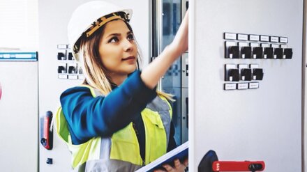 Flexibilitätsvermarktung für Kraftwerke Frau mit Helm vor Schaltschrank