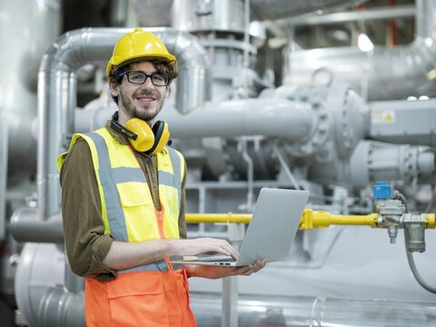 EWE Versprechen Ein Mann in gelber Weste und mit Helm prüft etwas in einem Unternehmen