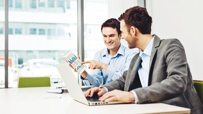 EWE business Strom logic Zwei Männer an einem Arbeitsplatz mit einem Laptop, die ein Diagramm ansehen