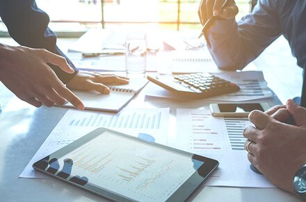 Standortvernetzung von EWE Schreibtisch mit Unterlagen, Taschenrechner, Tablet und Smartphone