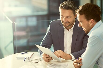 Standortvernetzung von EWE Zwei Männer im Business-Look schauen auf Tablet