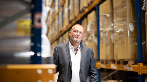 EWE Leased Line Mann im Anzug in Lagerhalle