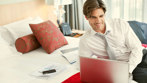 Profi-WLAN von EWE für Gäste Mann liegt mit Laptop auf Hotelbett