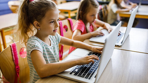 Digitalisierung in der Schule Zwei Mädchen an Schultischen mit Laptops
