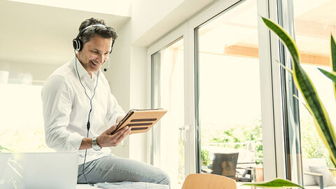 SIP Trunk von EWE Mann mit Tablet in der Hand telefoniert mit Headset