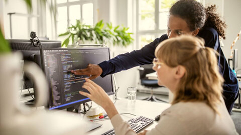 So funktioniert EWE DDoS-Schutz Zwei Frauen schauen gemeinsam auf einen Computer-Bildschirm