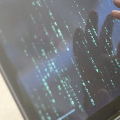 EWE DDoS-Schutz Hand eines stilisierten Hackers auf Laptop-Bildschirm
