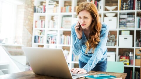 Mobilfunk für das Home Office Eine Frau lehnt auf ihrem Schreibtisch und telefoniert.