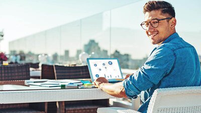 EWE business Strom fix Ein Mann auf einer Dachterrasse an einem Laptop